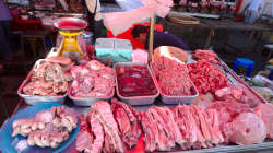 Trh na ulici, větrák s igelitkama odhání mouchy z masa. Venku je okolo 30 nad nulou