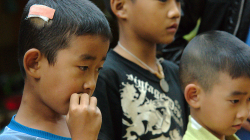 Děti uloveného hada pozorují z úctivé vzdálenosti